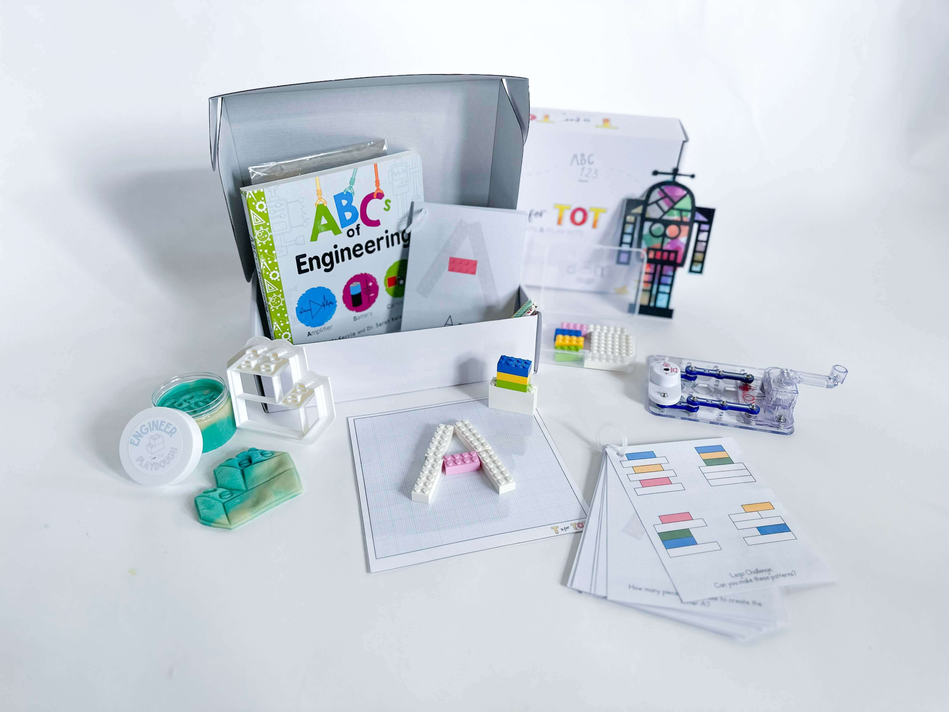 STEM-focused play and learn kit for kids aged 3-6. Includes a battery-free snap circuit, Lego playdough cutter with homemade playdough, straw STEM activity, Robot Suncatcher, Lego pieces, Lego educational cards, and